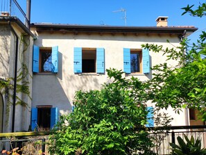 A two-story building with blue shutters, a visible chimney, and a tree in the foreground. - Kaletheia house - restored mill (Volpago del Montello (TV))