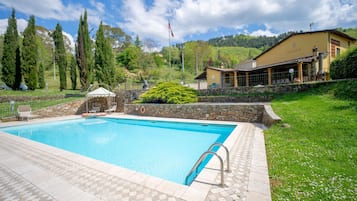 Relax by the serene pool surrounded by lush greenery and a shaded gazebo.