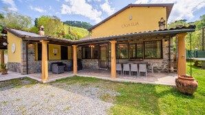 Un bâtiment jaune doté d’un patio couvert, de piliers en pierre et d’un espace extérieur aménagé avec des sièges.