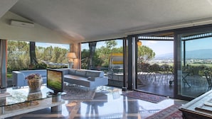 A spacious living room with a large window, a sofa, a coffee table, and a TV.