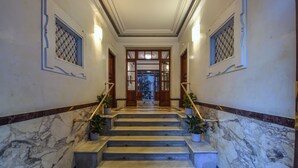 Una scala in marmo con ringhiere, piante in vaso e vista su una stanza con un'ampia finestra.