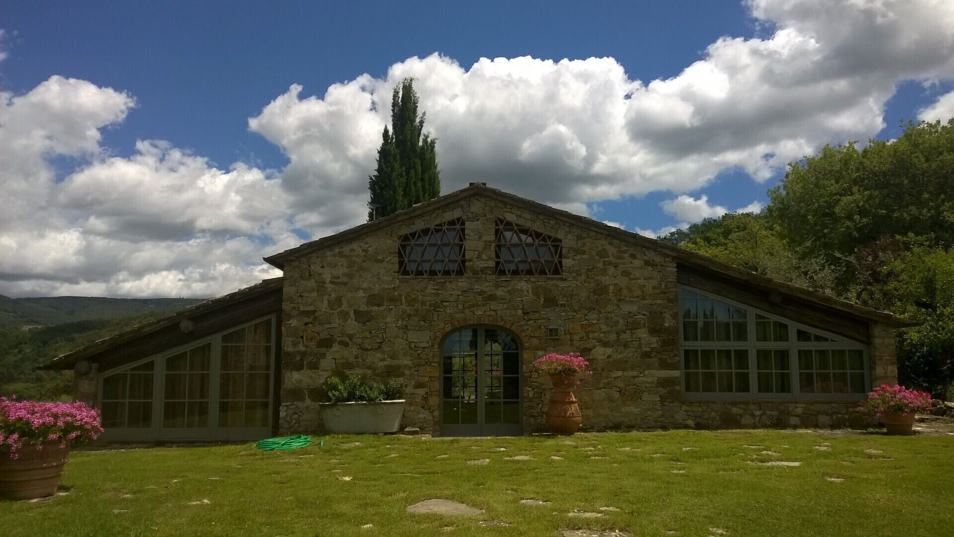 A stone building with large windows and a green lawn.