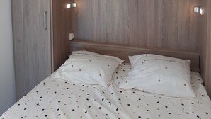 A bedroom with a wooden headboard, a bed with polka dot bedding, and two wall-mounted reading lights. - Apartment/ flat - Quiberon (Quiberon)