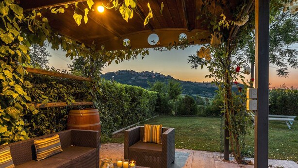 Un espace extérieur aménagé avec des meubles en osier et offrant une vue sur une colline.