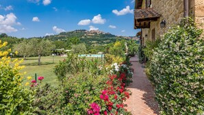 Un bâtiment en pierre avec un sentier de jardin menant à une zone avec piscine.