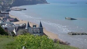 A coastal town with buildings near the beach, a cliff, and the sea. - Norman house with garden near the landing beaches  (Ver-Sur-Mer)