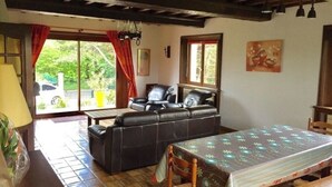 A cozy living room with a sofa, a dining table, and a view of the outdoors. - Norman house with garden near the landing beaches  (Ver-Sur-Mer)