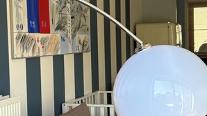 Un salon moderne avec un mur à rayures, un lampadaire blanc et un canapé gris.