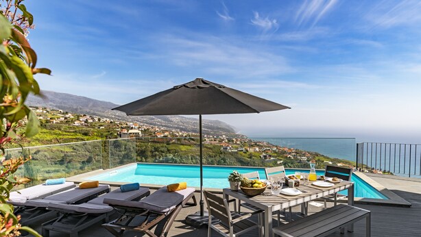 A terrace with a pool, lounge chairs, and a table set for breakfast. - Villa Clementina | Cliffs & Ocean | Heated Pool 26ºC (Prazeres)