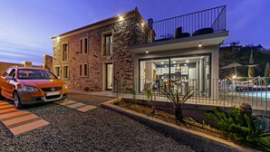 A modern house with a stone facade, a glass front, and a balcony. - Villa Clementina | Cliffs & Ocean | Heated Pool 26ºC (Prazeres)