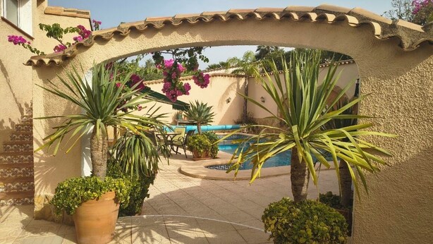 Un patio con piscina, plantas en macetas y una pérgola.