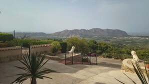 Un patio con vistas a las montañas, una moto roja y una estatua.