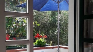 Een balkon met een tafel, stoelen en een blauwe parasol.