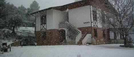 A two-story building with a staircase leading to the entrance, surrounded by snow-covered ground.