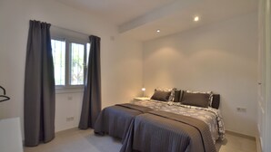 A bedroom with two beds, a window with curtains, and a bedside table with a lamp. - House, 3 terraces, directly on golf course, swimming pool, tennis. Close to beach (Nueva Andalucia,)