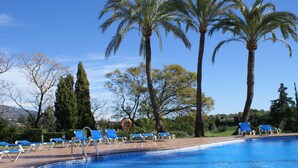 A swimming pool with blue water, surrounded by palm trees and lounge chairs. - House, 3 terraces, directly on golf course, swimming pool, tennis. Close to beach (Nueva Andalucia,)