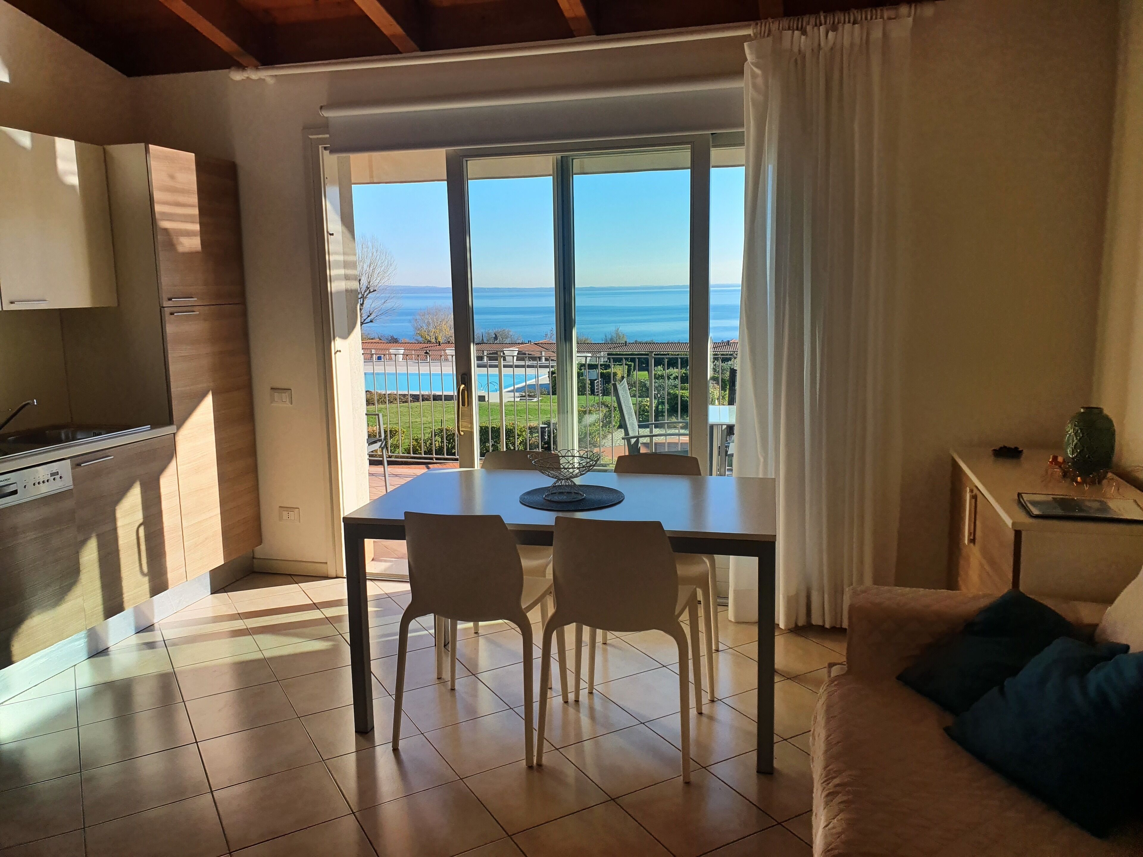 Une cuisine moderne avec vue sur la mer, un coin repas avec des chaises et un canapé agrémenté de coussins.