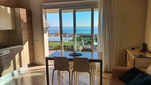 Une cuisine moderne avec vue sur la mer, un coin repas avec des chaises et un canapé agrémenté de coussins.