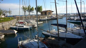 Un port de plaisance où sont amarrés de nombreux bateaux, un petit bâtiment et un mur de pierre.