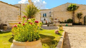 Un patio con muros de piedra, una fuente y plantas en macetas.