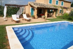 Une piscine avec des chaises longues et un espace de détente abrité.