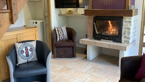 A living room with a fireplace, a television mounted above it, and a staircase leading to an upper level.