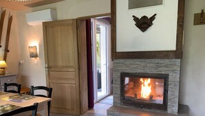 A cozy room with a fireplace, a dining table with chairs, and a wooden door.