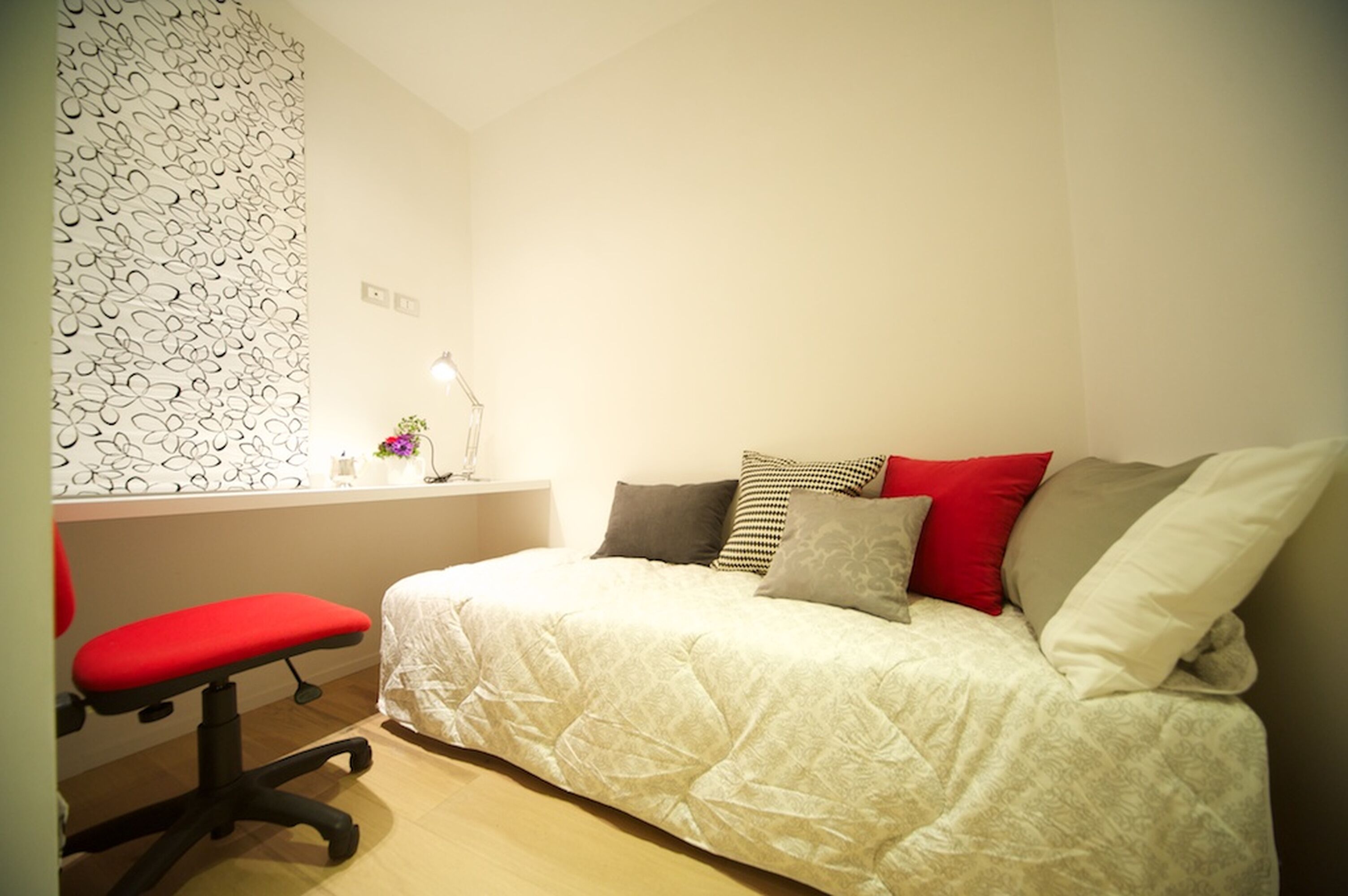 A bedroom with a bed, a desk, and a chair.