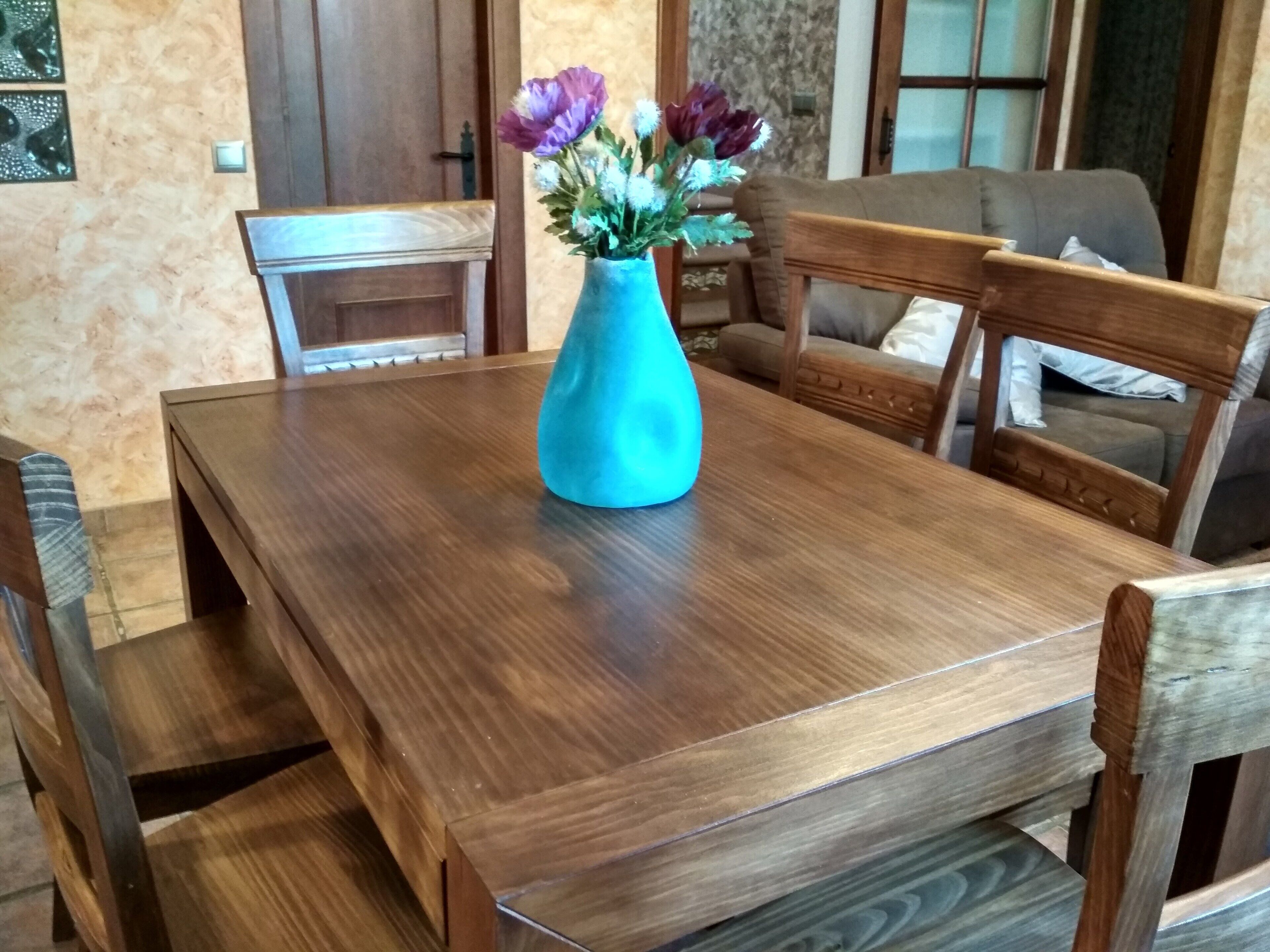 Een houten eettafel met een bloemenvaas.