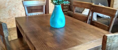 Een houten eettafel met een bloemenvaas.
