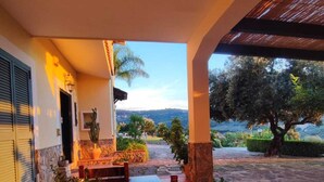A covered outdoor area with a wooden bench, a bowl of fruit, and a view of a natural landscape. - Wonderful villa with pool in a panoramic position at the gateway to Cilento. (Ogliastro Cilento)