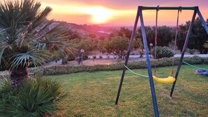 A swing set in a grassy area with a sunset view. - Wonderful villa with pool in a panoramic position at the gateway to Cilento. (Ogliastro Cilento)