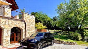 Un VUS noir était garé devant un bâtiment en pierre, avec un chemin d’accès en briques rouges menant à l’entrée.