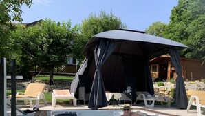Une piscine avec un jacuzzi, des chaises longues et un espace salon couvert.
