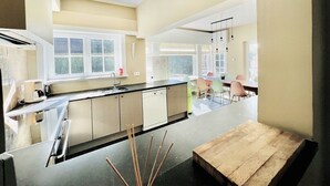 A modern kitchen with a large island, a dining area with colorful chairs, and a view of the outdoors.