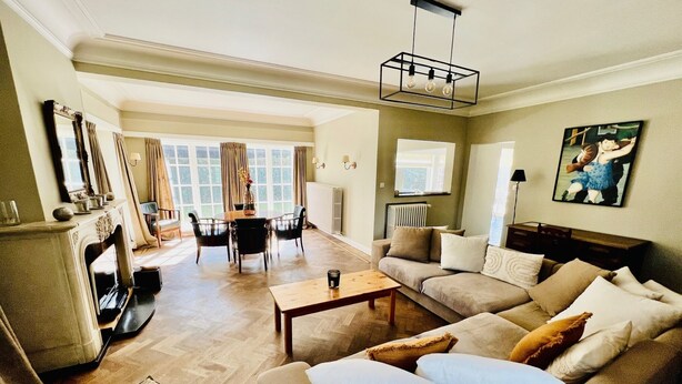 A spacious living room with a fireplace, a dining area, and a sofa set.