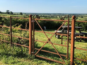 Une porte en métal rustique, avec une table de pique-nique, dans un champ herbeux.
