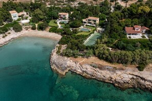 A coastal property with multiple houses, a tennis court, and a beach.