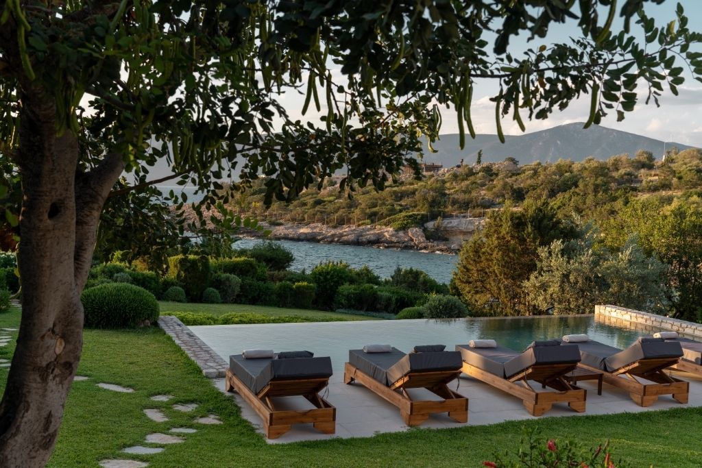 Zona de piscina con sillones de descanso y vista a un paisaje natural.