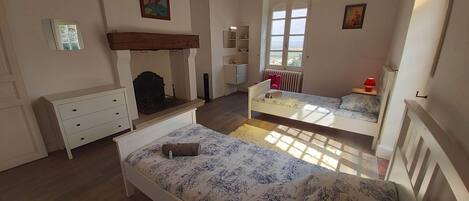 A bedroom with two beds, a dresser, a mirror, a radiator, and a window.
