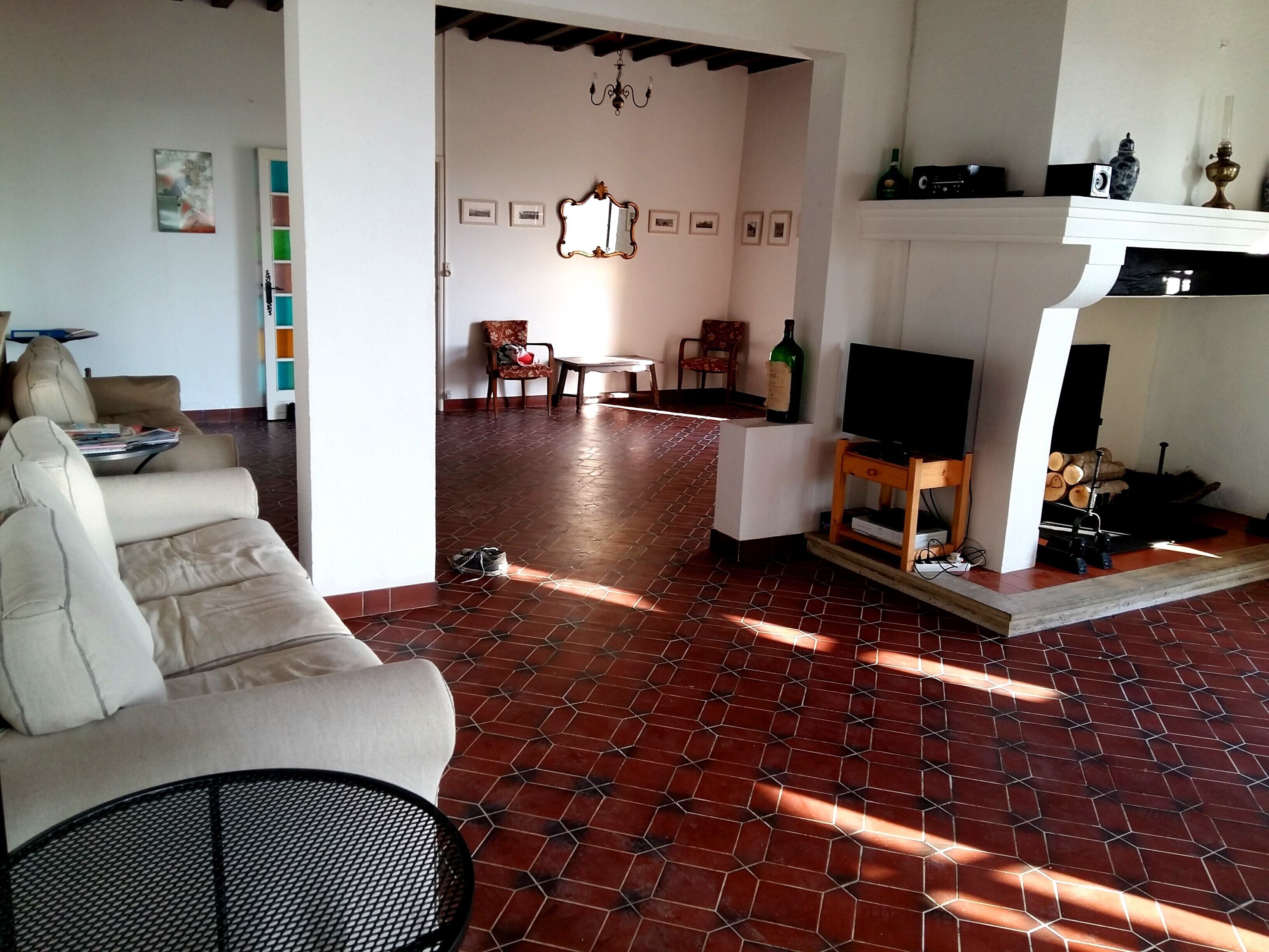A living room with a sofa, a TV, and a fireplace. There are chairs and a table in the background.