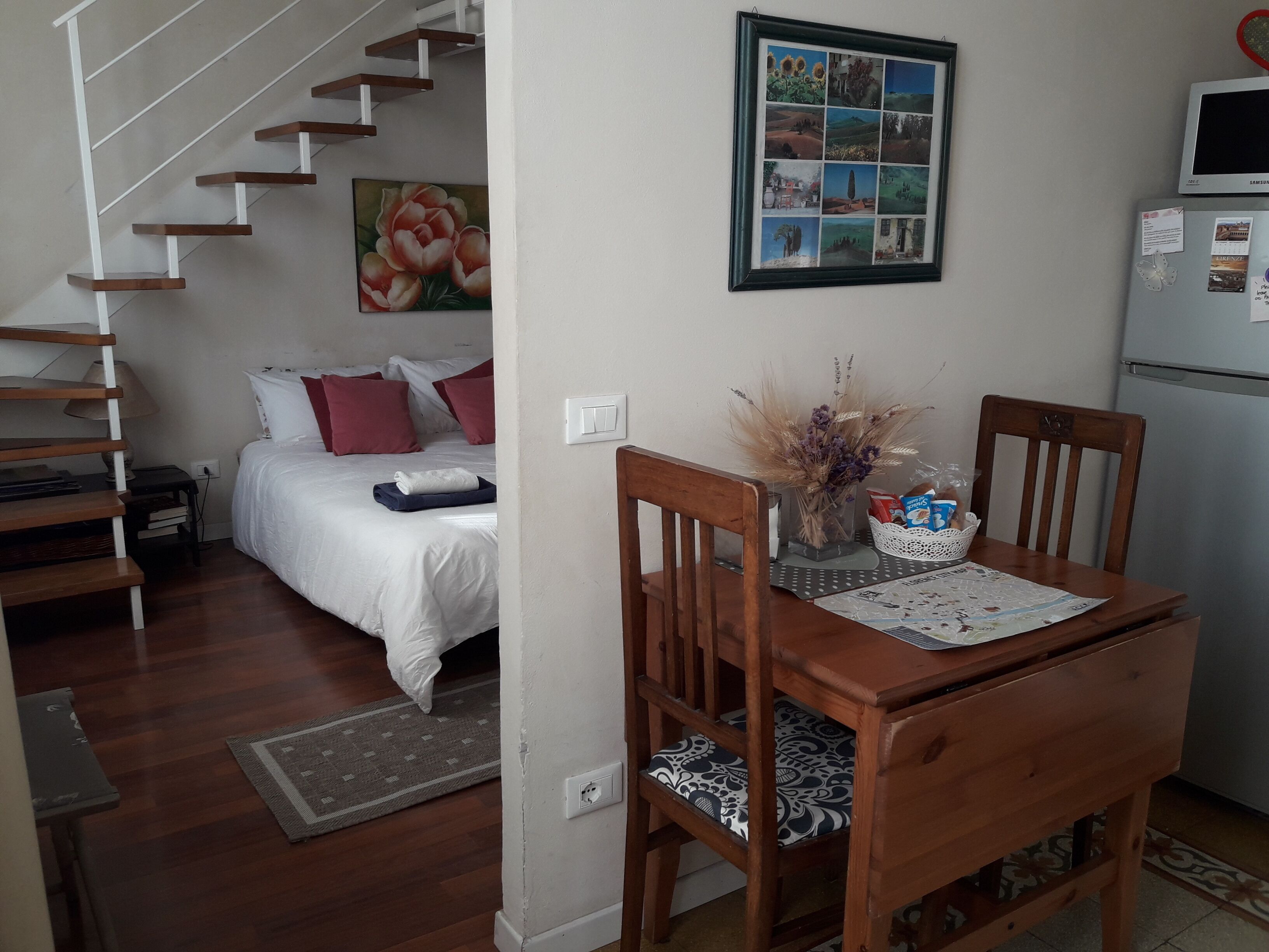 A bedroom with a bed, a nightstand, and a dresser. There is a staircase leading to another level.