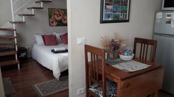 A bedroom with a bed, a nightstand, and a dresser. There is a staircase leading to another level.