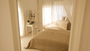 Une chambre à coucher avec un lit, une table de chevet, un miroir et une fenêtre avec des rideaux.