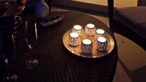Un salon avec une table basse en verre, un canapé et une table à manger décorée de bougies.