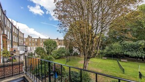 A residential area with terraced houses, a tennis court, and a large tree. - The One Kensington (London)
