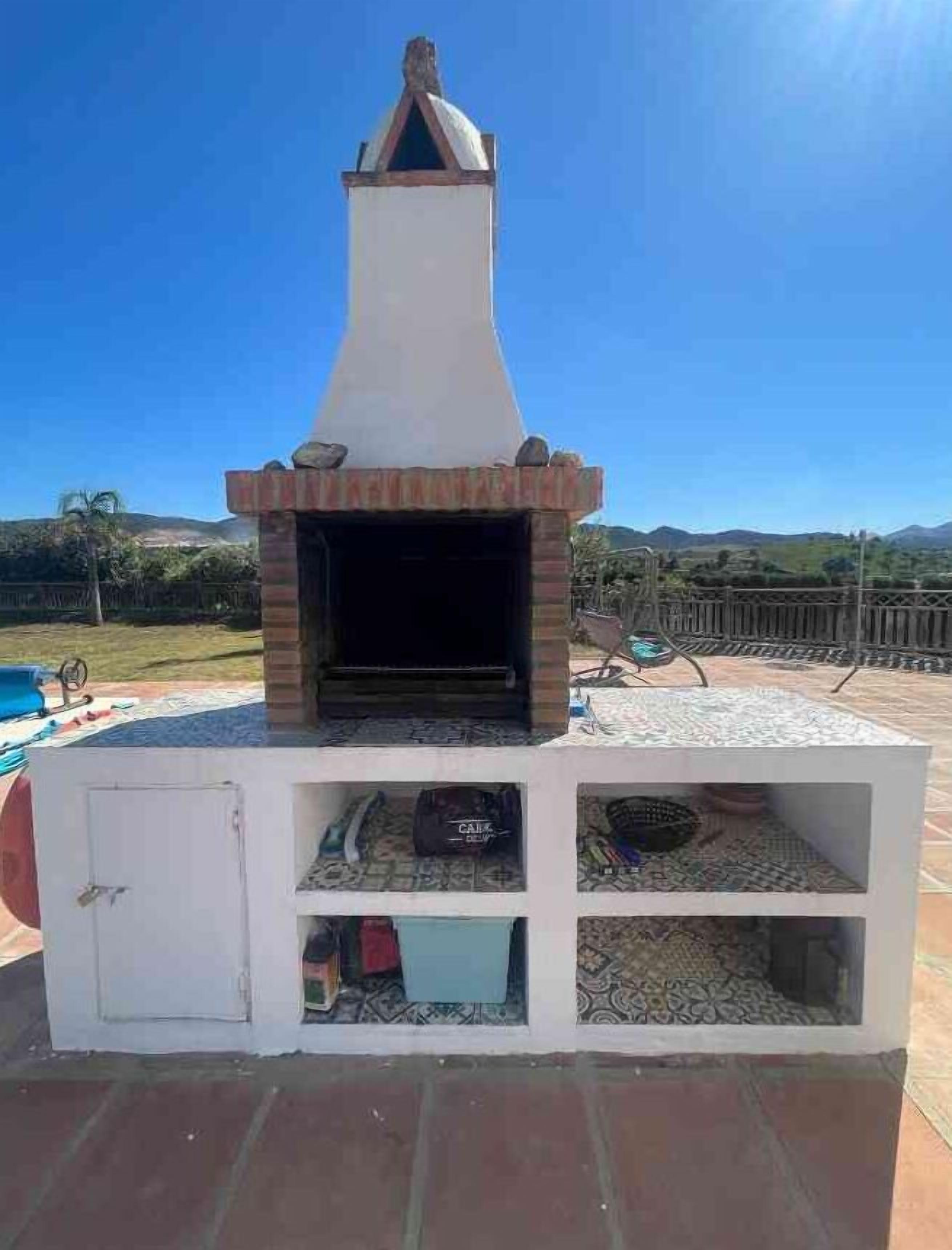 A brick-built outdoor oven with a chimney, surrounded by a tiled patio.