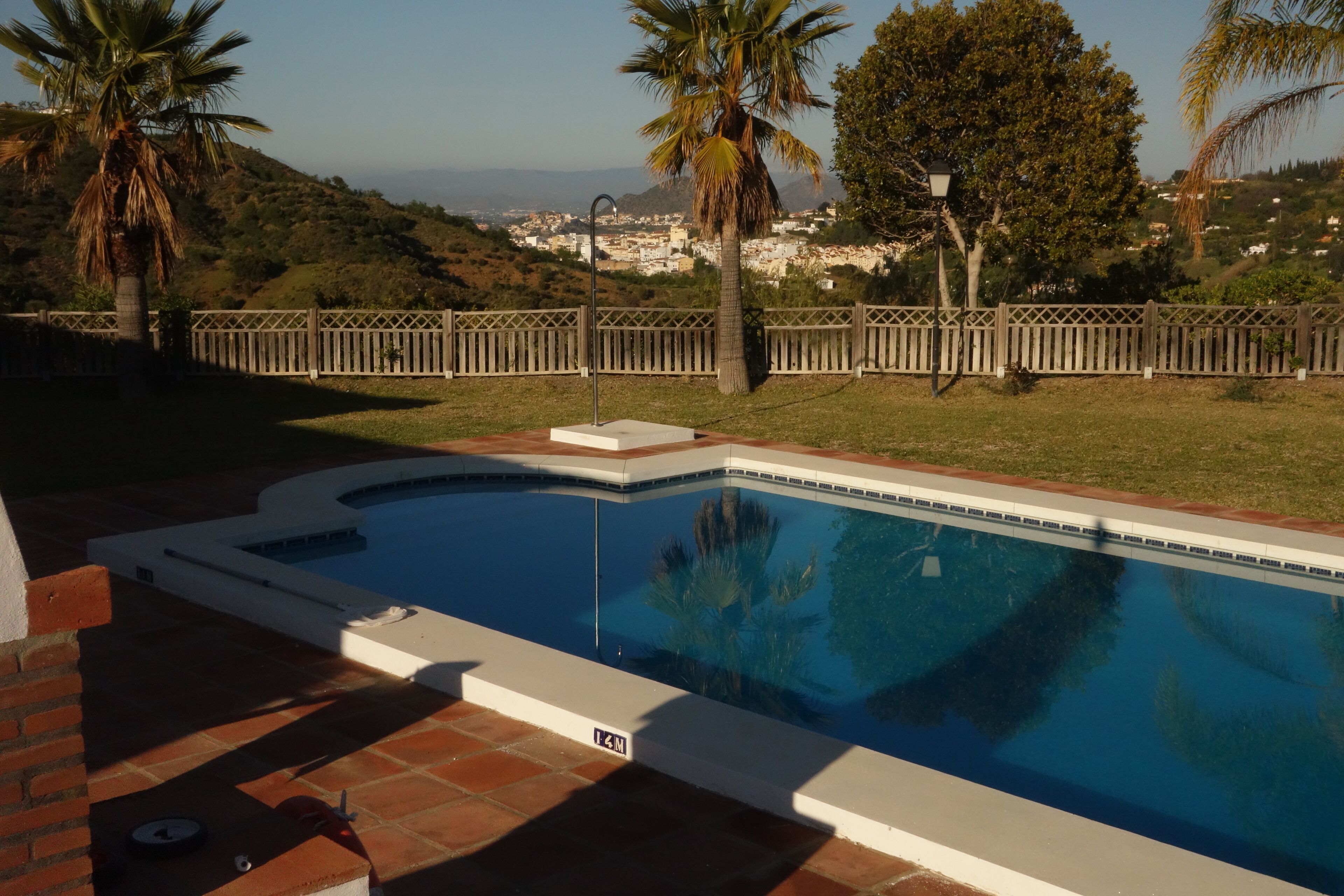 A swimming pool with a view of a hillside and a wooden fence.