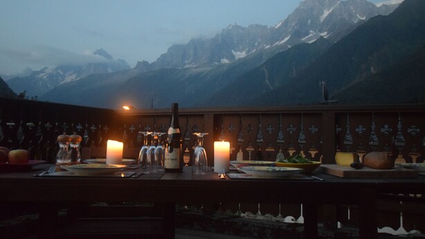 Une table dressée pour un repas, avec une vue sur les montagnes en arrière-plan.