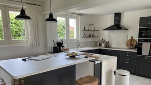 Une cuisine moderne dotée d’un grand îlot central, de meubles de rangement noirs et d’une hotte aspirante noire.